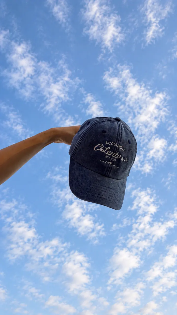 Il cappello Acciaroli blu tenuto in alto contro il cielo